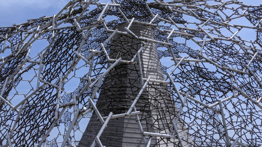 The intricate lattice structure of the Rokko-Shidare Observatory at Rokko Garden Terrace in Kobe, captured against a clear blue sky, symbolizing the architecture of silence.