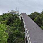 A view of the long Carlator slope leading up to the white revolving observatory surrounded by lush green trees in Sumaura Park, Kobe.