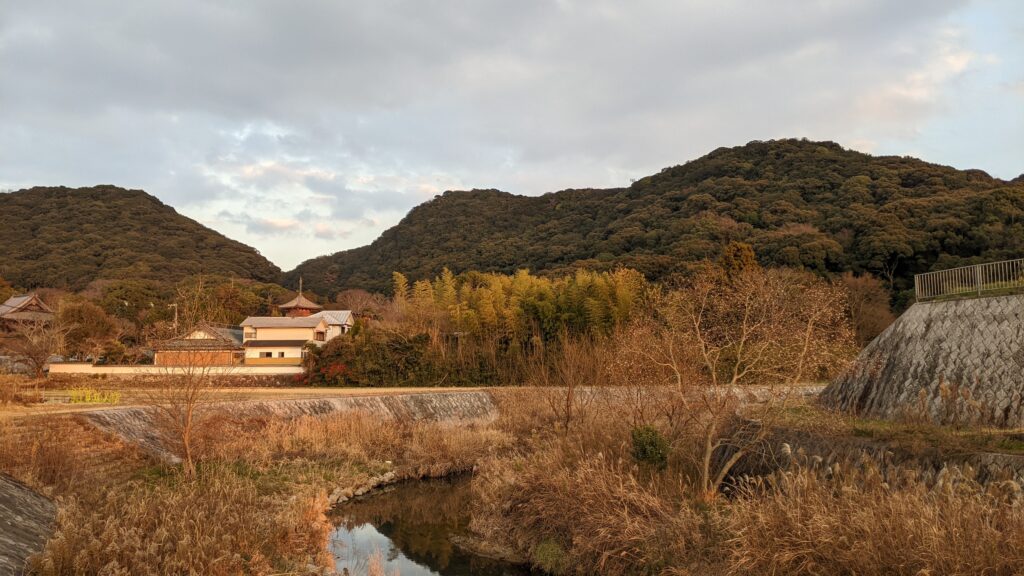A serene rural scene in Nishi-ku, Kobe, featuring a quiet river and lush mountains. This landscape serves as the primary inspiration for the Nishi-ku area in the kodiad metaverse, capturing the "Architecture of Silence."